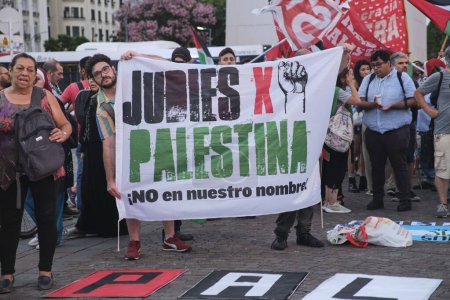 Foto de Buenos Aires, Argentina, 16 de febrero de 2024: la gente protesta en solidaridad con Palestina, contra la violencia sionista y el genocidio israelí. Banner con el texto Judios para Palestina. No en nuestro nombre.! - Imagen libre de derechos