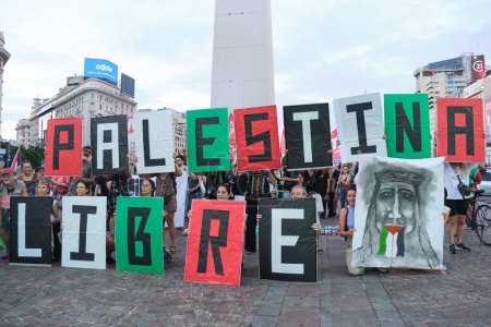 Foto de Buenos Aires, Argentina, 16 de febrero de 2024: Protestan frente al obelisco, en el centro de la ciudad, con carteles en los colores de la bandera palestina que forman el texto Free Palestine. - Imagen libre de derechos