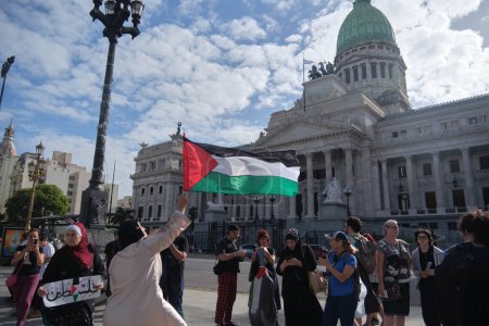Foto de Buenos Aires, Argentina, 16 de febrero de 2024: Mujer levantando una bandera palestina, la gente se reunió frente al Congreso Nacional en solidaridad con Palestina y contra el ataque genocida de Israel. - Imagen libre de derechos