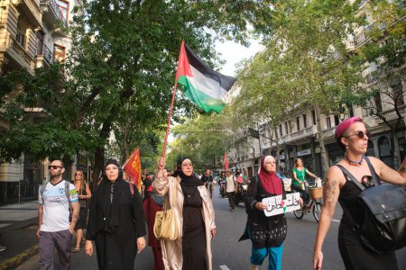 Foto de Buenos Aires, Argentina, 16 de febrero de 2024: Marchan con una bandera palestina en solidaridad con Palestina contra el genocidio israelí. - Imagen libre de derechos