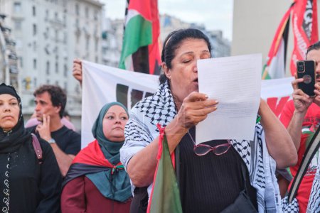 Foto de Buenos Aires, Argentina, 16 de febrero de 2024: Personas protestando en el centro de la ciudad en solidaridad con Palestina y contra el ataque genocida de Israel. Mujer leyendo un manifiesto pacifista. - Imagen libre de derechos