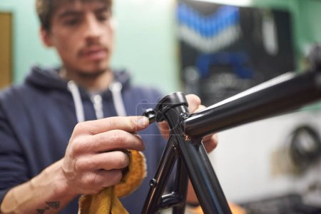 Junger hispanischer Mann baut in seinem Fahrradladen ein Fahrrad im Rahmen eines Wartungsdienstes zusammen. Echte Menschen bei der Arbeit.