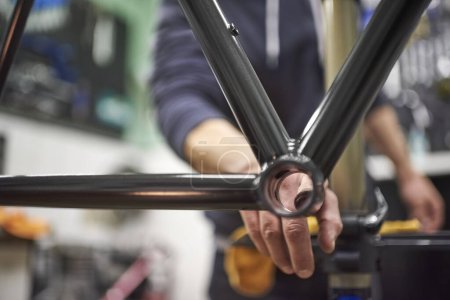 Personne méconnaissable assemblant un vélo dans son atelier de vélo dans le cadre d'un service d'entretien. De vraies personnes au travail.