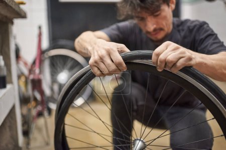Der lateinische Fahrradmechaniker montiert in seiner Werkstatt einen luftlosen Vollreifen an einem Rad. Selektive Fokuskomposition mit Kopierraum.