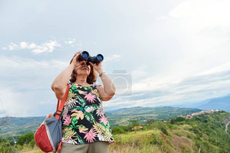 Unbekannte Frau beobachtet Barichara, die schönste Stadt Kolumbiens, von einem Aussichtspunkt aus durch ein Fernglas.