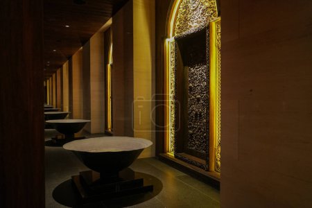 Espace intérieur élégant mettant en valeur le contraste entre les panneaux traditionnels en bois sculpté et l'élégance moderne d'une table en marbre, le tout sous un éclairage chaleureux et ambiant