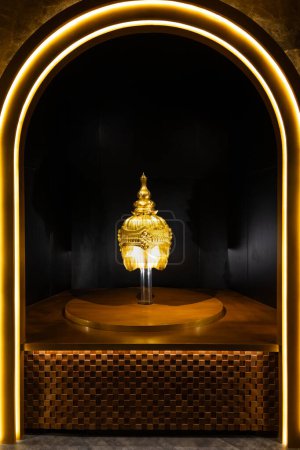 Foto de Una alcoba bellamente iluminada enmarcando una escultura de casco tradicional dorada, ejemplificando la geometría sagrada y el arte cultural en la arquitectura - Imagen libre de derechos
