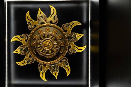 A striking wall-mounted golden solar emblem, combining traditional motifs with modern presentation, creating a bold artistic statement