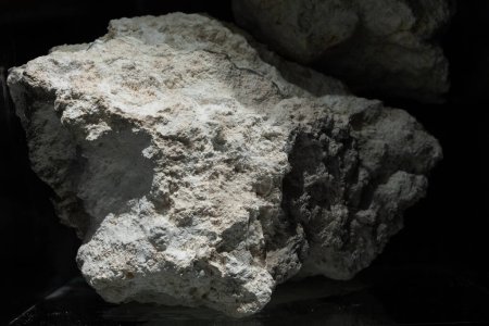 A close-up shot of a natural rock formation with rich textures and complex details, highlighted against a dark background for dramatic effect