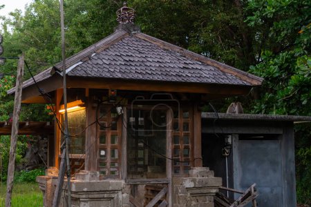 A traditional wooden pavilion stands in a serene setting while two wild monkeys sit together on the roof, showcasing Balinese architecture and wildlife coexistence.