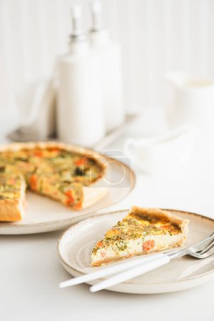 French quiche lauren with salmon, cheese and broccoli on white table. Soft focus