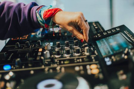 DJ plays live set and mixing music on turntable console on stage at nightclub. Disc Jockey Hands on a sound mixer station at club party. SELECTIVE FOCUS
