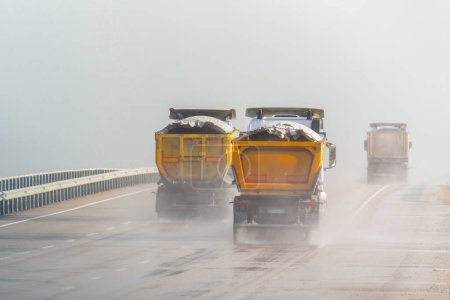 Sand lorries driving on motorway in the rain. Motorway in the rain.