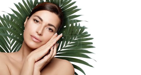 Photo for Organic Beauty and Skincare Concept. Natural young woman with fresh hydrated and glowing skin against green exotic plants isolated on white background. Horizontal format with copy space. - Royalty Free Image