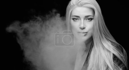 Foto de Hermosa mujer sexy soplando humo. Retrato de estudio monocromo aislado en negro con espacio de copia - Imagen libre de derechos