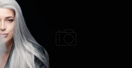 Cropped view of smoker woman blowing smoke. Silver haired woman isolated on black background with copy space.