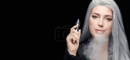 Photo for Vaping girl. Silver haired woman blowing a big smoke cloud. Female with an Electronic Cigarette isolated on black background with copy space - Royalty Free Image