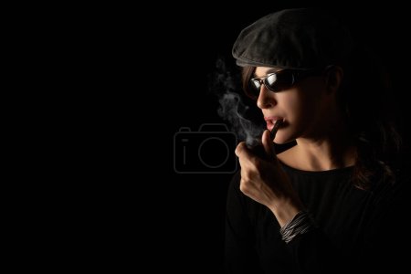 Téléchargez les photos : Atractive hipster girl smoking vintage wooden pipe. Studio portrait isolated on black background with copyspace - en image libre de droit