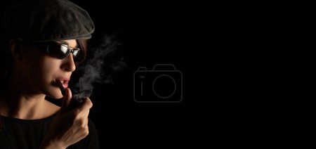 Téléchargez les photos : Atractive hipster girl smoking a vintage wooden pipe. Panorama banner studio portrait isolated on black background with copyspace - en image libre de droit
