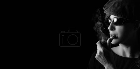 Foto de Atractive hipster girl smoking vintage wooden pipe. Studio portrait isolated on black background with copyspace - Imagen libre de derechos