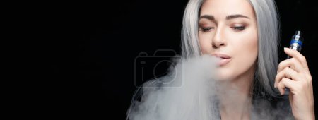Vaping girl. Silver haired woman blowing a big smoke cloud. Female with an Electronic Cigarette isolated on black background with copy space