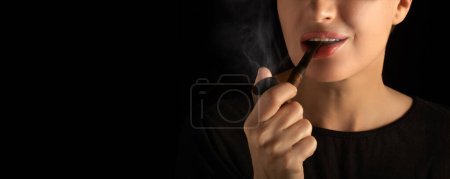 Photo for Wman smoking pipe. Smoking lady with a vintage wooden pipe. Cropped studio portrait isolated on black background - Royalty Free Image