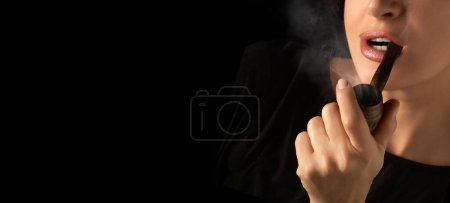 Foto de Wman fumando pipa. Dama fumadora con pipa de madera vintage. Retrato de estudio recortado aislado sobre fondo negro - Imagen libre de derechos