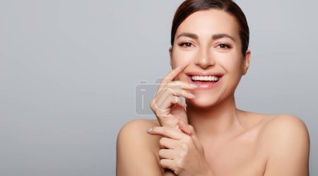 Photo for Beauty and skin care concept. Natural young woman with fresh glowing skin smiling at camera. Studio portrait on gray background with copy space - Royalty Free Image