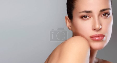 Photo for Beauty and Skincare Concept. Beautiful natural young woman face with nude makeup on a flawless skin. Beauty portrait on gray background with copy space - Royalty Free Image