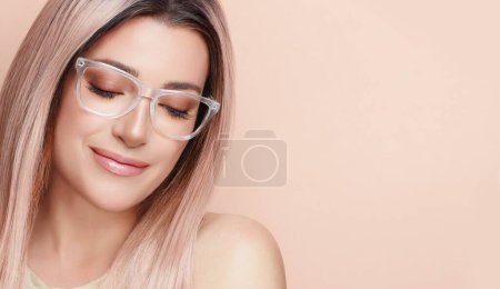 Foto de Mujer hermosa sonriente en gafas claras sobre fondo beige. Visión clara y concepto de salud visual - Imagen libre de derechos
