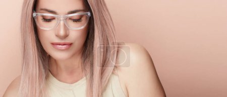 Photo for Women eyewear. Beautiful young woman in fashionable clear glasses looking at camera posing in studio. Fashion eyewear and clear vision concept. Beauty portrait over beige background with copy space - Royalty Free Image