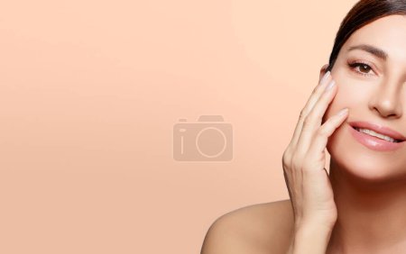 Photo for Beauty and Skincare Concept. Beautiful natural woman face with nude makeup on a flawless skin. Half face portrait over beige background with copy space - Royalty Free Image