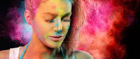 Foto de Mujer de la cara de belleza cubierta de polvo de holi con una explosión de color arco iris en el fondo. Festival de colores concepto. Panorama Banner con espacio de copia - Imagen libre de derechos