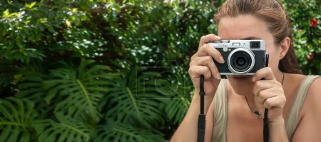 Téléchargez les photos : Une femme prenant des photos avec un appareil photo vintage à l'extérieur. Concept de voyage et de photographie. Panorama bannière avec espace de copie - en image libre de droit