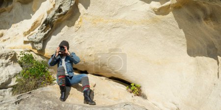 Foto de Capturing Adventure: Woman Exploring Rock Formation with Camera. Copiar espacio. - Imagen libre de derechos