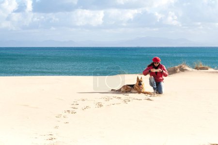 Téléchargez les photos : Personne et chien sur la plage, profitant de paysages côtiers magnifiques et d'une escapade de vacances sereine. Avec copyspace. - en image libre de droit