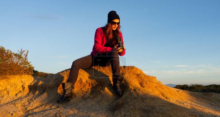 Téléchargez les photos : Une femme en tenue décontractée photographie des paysages de montagne époustouflants contre un ciel limpide.. - en image libre de droit