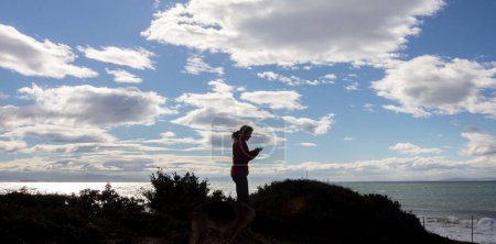 Téléchargez les photos : Une femme capture la beauté de la nature sur une plage, avec l'océan et le ciel en arrière-plan à Tarifa, en Espagne. Avec espace de copie. - en image libre de droit