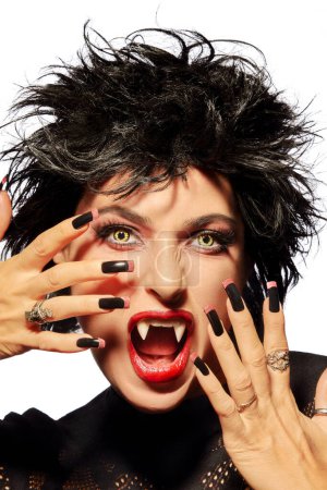 Photo for Woman expressing rage, screams with open mouth, wide eyes and exposed teeth. The Halloween costume that resembles a vampire or wolf adds a spooky touch. Intense emotions captured in this portrait. - Royalty Free Image