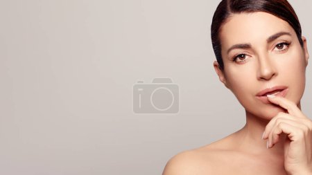 Photo for Confident middle aged radiating natural beauty with clear, glowing skin. The close-up captivates with a captivating look. Perfect for skin care and rejuvenating experiences in a spa or studio. - Royalty Free Image