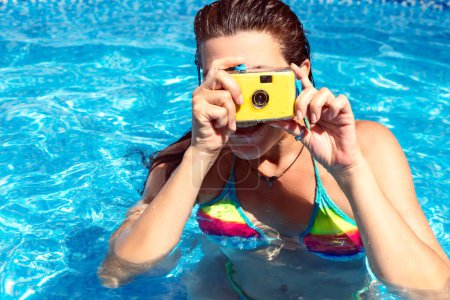 Téléchargez les photos : Une femme dans une piscine utilisant une caméra sous-marine rétro. Fermer avec espace de copie - en image libre de droit