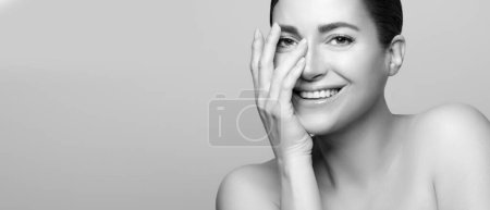 Photo for Radiant woman with natural beauty, flawless skincare and smiling face, monochrome portrait, indoor setting. Panorama banner with lateral copyspace. - Royalty Free Image