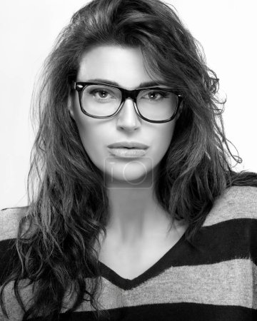 Photo for Confident young woman with brown hair, glasses, and minimal make-up. Her fashion-forward portrait, in black and white, highlights her beauty and stylish eyewear. - Royalty Free Image