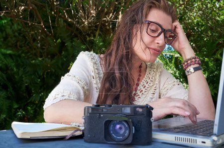 Photo for A young adult freelancer works on a laptop outdoors, surrounded by greenery and foliage, blending work with exploration. - Royalty Free Image