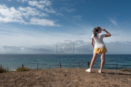 Photo for A confident woman on a beach gazes at the horizon. The calm ocean and dreamy sky create a serene backdrop for her contemplative self-care and self-expression. - Royalty Free Image
