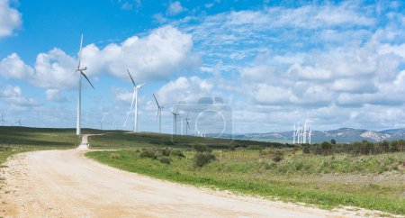 Foto de Fila de molinos de viento contra un cielo nublado, mostrando energía sostenible en un paisaje natural. - Imagen libre de derechos