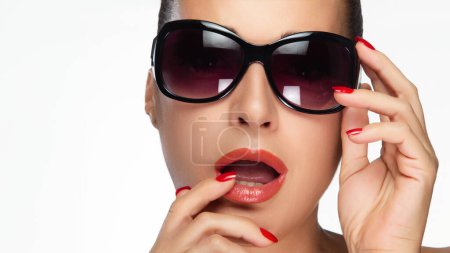 Foto de Modelo glamuroso con gafas de sol aisladas en blanco, evocando alta moda. Capta la atención con sus elegantes gafas y su pose segura. - Imagen libre de derechos