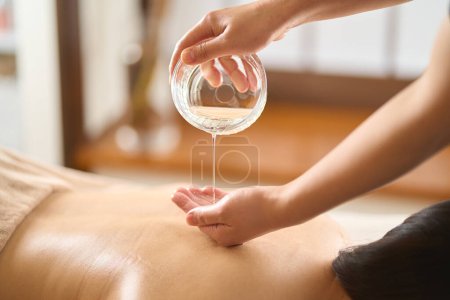 Esthéticienne goutte à goutte huile de massage au salon de beauté