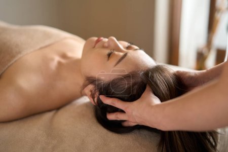 Téléchargez les photos : Femme recevant un massage de la tête au salon de beauté - en image libre de droit