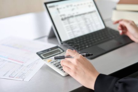 Téléchargez les photos : Asian woman using accounting software and calculator - en image libre de droit